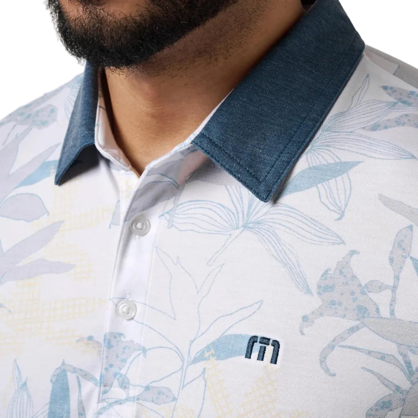 Close-up of a person wearing a white polo shirt with blue floral pattern and denim collar, featuring a brand logo.