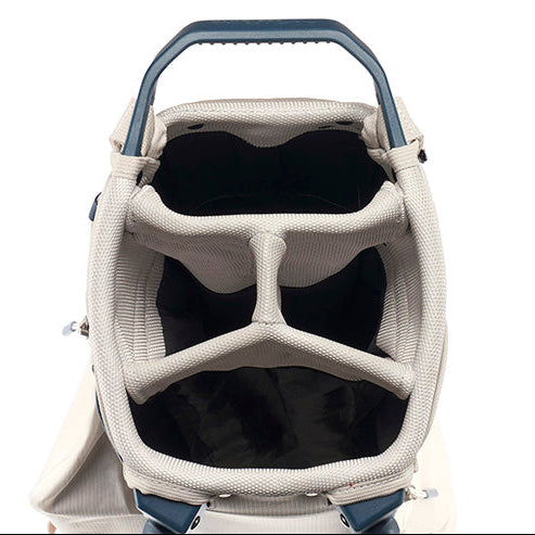 Close-up of the top opening of a golf bag, showing a beige textured exterior, a dark blue handle, and a black interior lining with internal dividers.