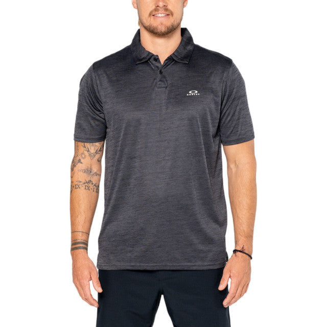 A male model wearing a black Oakley Hydrolix Galaxy Polo with a two-button collar and the Oakley logo on the center top back.