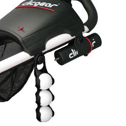 A close-up of the Clicgear Trundler Golf Ball Clip attached to a golf cart, displaying a black and red color scheme with the ability to hold three golf balls.