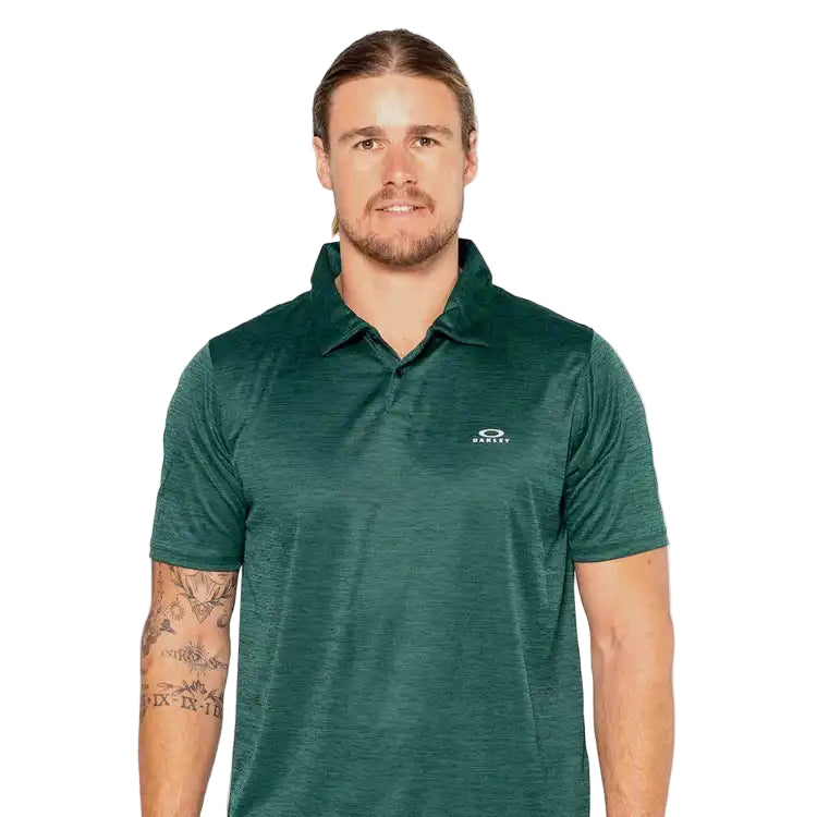 Man wearing a green polo shirt with a logo on a light gray background