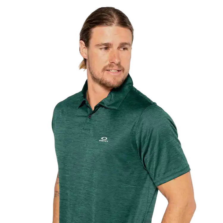 Man wearing a green polo shirt with a brand logo on a light background