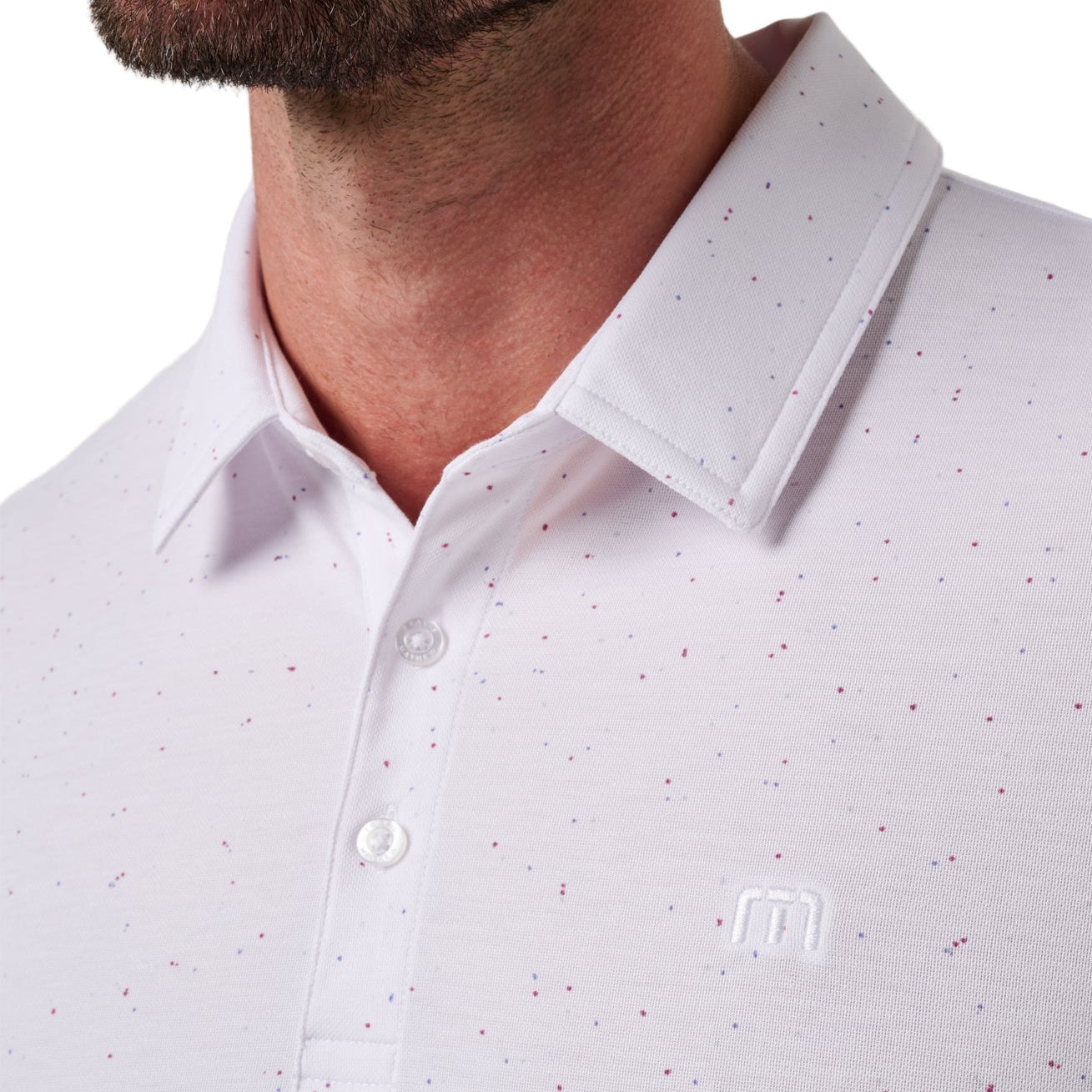 White polo shirt with subtle pattern worn by a person, brand logo visible.