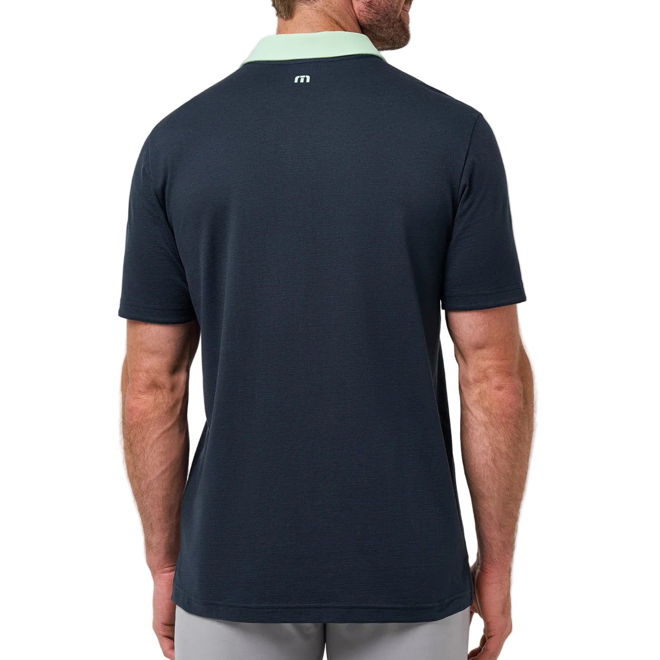 Man wearing a navy blue athletic shirt with a logo on the back against a white background