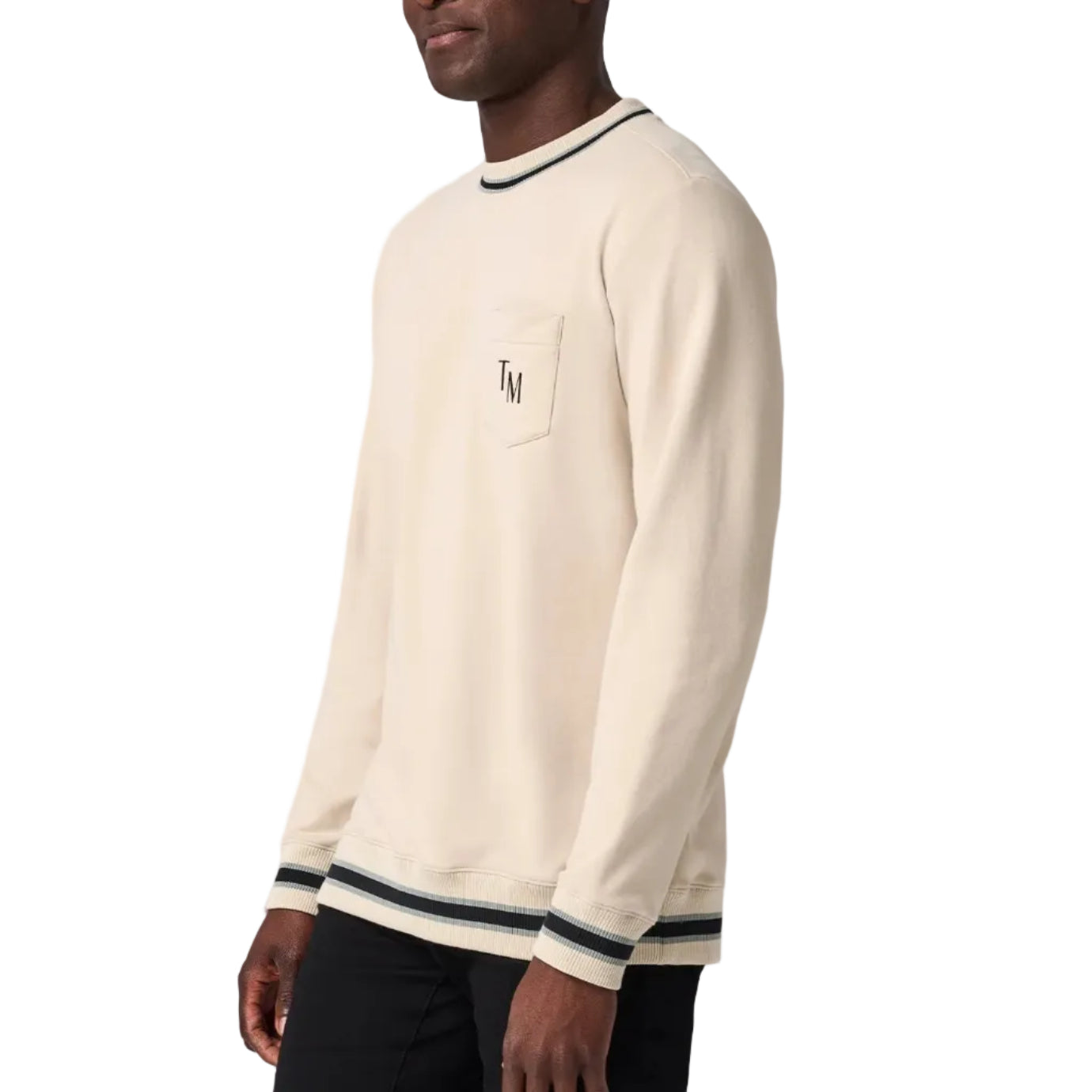 Man wearing a cream sweater with black trim on a white background