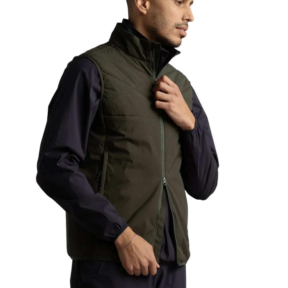 Man wearing a green puffer vest over a black jacket on a white background