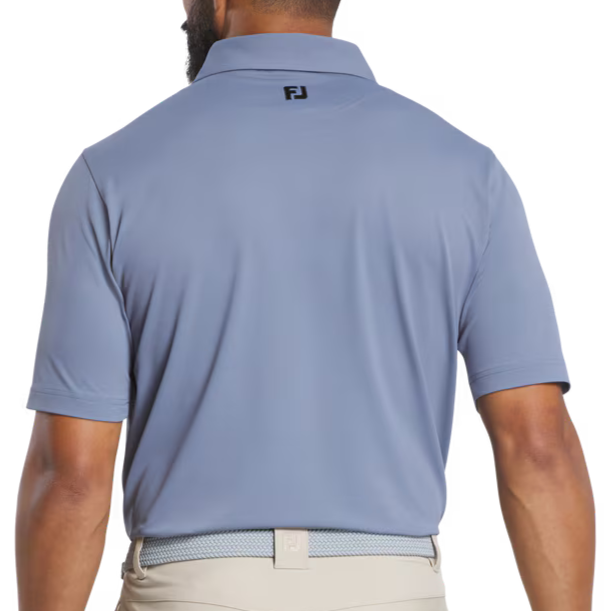 Man wearing a light blue polo shirt with a logo on the back, standing against a white background.