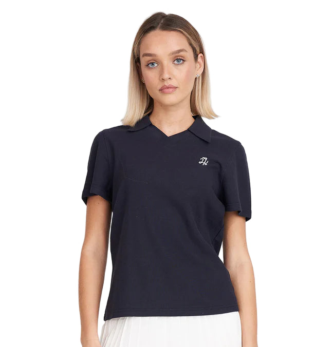 Woman wearing a navy blue polo shirt with a logo and a white skirt on a white background