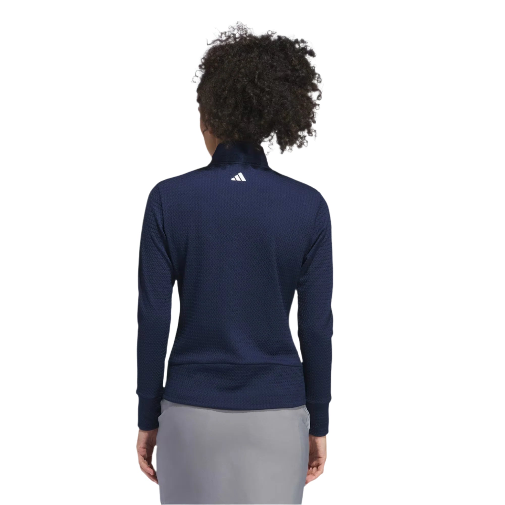 Person wearing a navy blue long-sleeve athletic shirt with a visible brand logo on the back, standing against a light gray background.